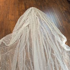 a wedding veil is laying on the floor with it's back covered in pearls