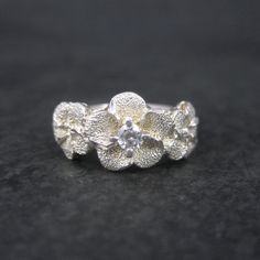 This beautiful flower ring is sterling silver with a cubic zircoia stone. The face of this ring measures 3/8 of an inch north to south. Size: 7 Marks: Peru, 925 Condition: Excellent Silver Flower-shaped Diamond Ring With Accents, Silver Flower Shaped Diamond Ring With Accents, Silver Flower Diamond Ring With Accents, Silver Diamond Ring With Flower Shape And Accents, Silver Flower Ring With Diamond Accents, Silver Flower-shaped Diamond Ring For Anniversary, Silver Flower Diamond Ring For Anniversary, Sterling Silver Flower Ring In Diamond White, Sterling Silver Flower Ring With Diamond Accents