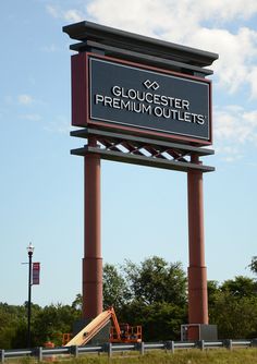 a large sign that says gloucesterer premium outlets in front of a park with playground equipment