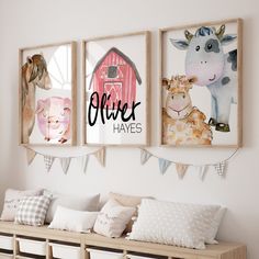 three farm animals are hanging on the wall above a wooden bench with pillows and blankets