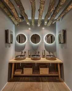 a bathroom with two sinks, mirrors and wooden beams in the ceiling is lit by lights