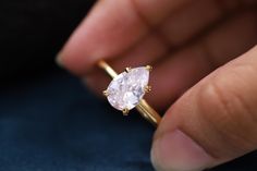 a close up of a person holding a ring with a white diamond in the middle