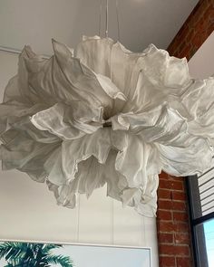 a large white light hanging from the ceiling in a room with brick walls and windows