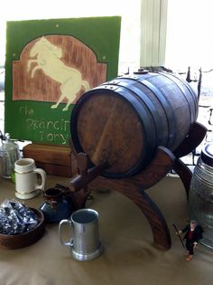 a wooden barrel sitting on top of a table next to two mugs and other items