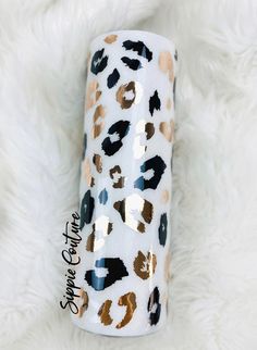 a white and black leopard print tube with gold foil on the top, sitting on a furry surface