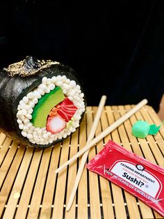 sushi with chopsticks on a bamboo mat next to a packet of candy