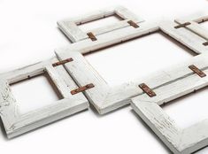 four white wooden frames are arranged on the floor with some rusted metal pins sticking out of them