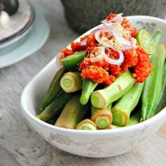 a white bowl filled with green vegetables on top of a wooden table next to other dishes