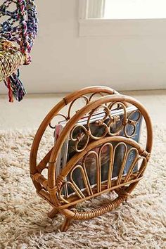 a magazine rack with magazines in it sitting on a carpeted floor next to a window