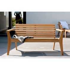 a wooden bench sitting on top of a patio next to two chairs and a blanket