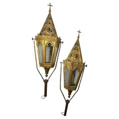 two ornate gold - plated metal lanterns with crosses on the top and sides, hanging from chains