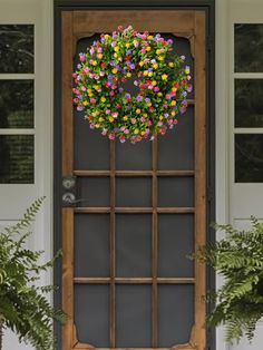 a bunch of flowers hanging from the side of a door with plants in front of it