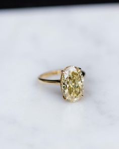 a yellow diamond ring sitting on top of a white counter