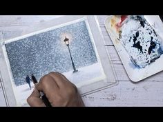 a person is painting on paper with watercolors