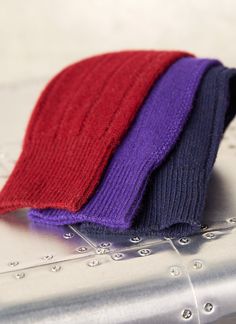 three different colored knitted hats sitting on top of an electronic device