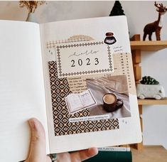 a person holding up a book with pictures on the pages and coffee cup in it