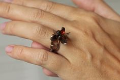 a woman's hand with a ring on it that has flowers in the middle