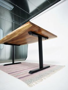 a wooden table sitting on top of a rug next to a metal frame and wall