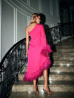 a woman in a pink dress standing on some stairs