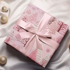 a pink gift box with a bow on top of it sitting on a white blanket