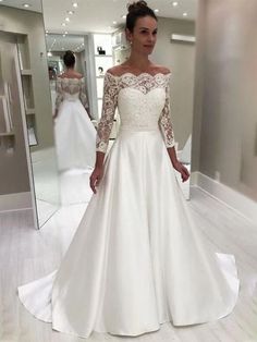 a woman in a white wedding dress is looking at the camera while standing in front of a mirror