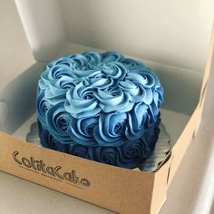 a blue frosted cake in a cardboard box