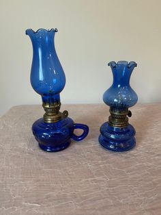 two blue glass vases sitting on top of a table