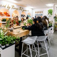 a group of women sitting around a table with plants