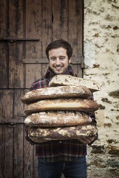 a man holding a large stack of bread