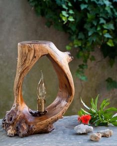 a wooden lamp sitting on top of a table next to rocks and plants in the background