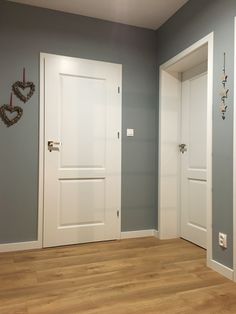 an empty room with two white doors and a wooden floor in front of the door