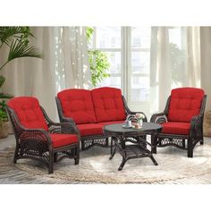 an outdoor living room with red cushions and wicker furniture on a rug in front of a window