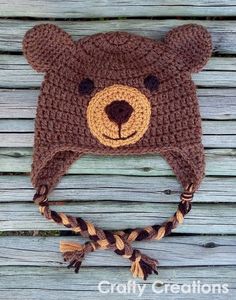 a crocheted brown bear hat on top of a wooden surface