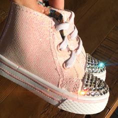 a close up of a person's foot wearing pink sneakers with crystal stones on them