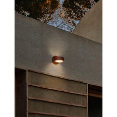 a light that is on the side of a building with trees in the back ground