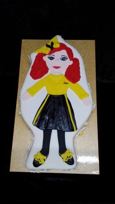 a cake shaped like a girl with red hair and yellow jacket on it's face