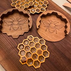 four wooden coasters with bees and honeycombs engraved on the sides, sitting on a table