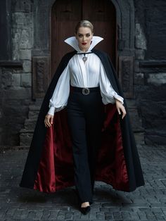 a woman in a white shirt and black pants with a red cape over her shoulders