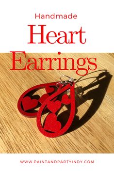 the words handmade heart earrings are cut out from red paper and placed on a wooden surface