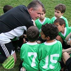 a coach is talking to his team on the soccer field with their players in a huddle