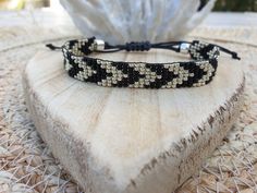 a black and white beaded bracelet sitting on top of a piece of wood