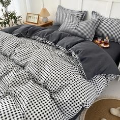 a bed with black and white checkered sheets, pillows and blankets on top of it