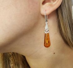 A beautifully crafted unique Baltic Amber pair of earrings. Featuring large teardrop shaped cognac Amber gemstones with a detailed sterling silver frame.Material: Authentic Baltic Amber and 925 sterling silverDimensions: 56 x 10 mm ( 2.20 x 0.39 in )Color: CognacFastening: Lever backFinish: PolishedThe Amber gemstones are a deep and classic cognac hue which shines brightly in natural light. The Amber teardrops are full of natural intricate flakes. The gorgeous open sterling silver work feature o Elegant Brown Teardrop Earrings For Gift, Elegant Brown Pierced Teardrop Earrings, Orange Teardrop Earrings For Formal Occasions, Elegant Brown Teardrop Pierced Earrings, Hypoallergenic Amber Teardrop Earrings, Formal Orange Teardrop Earrings, Brown Teardrop Earrings For Formal Occasions, Amber Teardrop Earrings, Formal Brown Teardrop Earrings