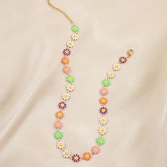 a multicolored flower necklace on a gold chain with an earring attached to it