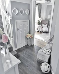 a white and gray living room with stairs leading up to the entrance way, flowers in vases on the floor