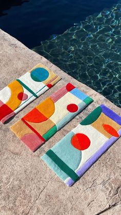 two towels sitting on the edge of a swimming pool next to a body of water