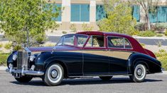 an old black and red car parked in front of a building