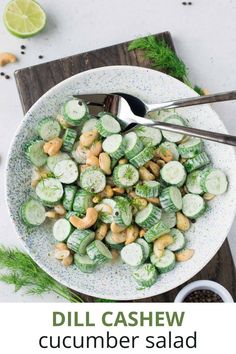 a white bowl filled with cucumber salad next to a spoon