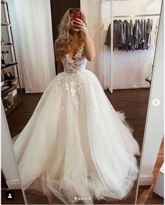 a woman taking a selfie while wearing a wedding dress in front of a mirror