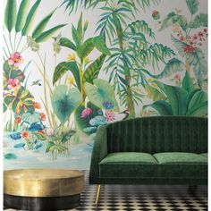 a green velvet couch sitting in front of a wall mural